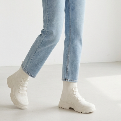 Bottines montantes tendance pour femme, design minimaliste avec col chaussette, semelle robuste et finition textile, photographiées en studio sur fond clair.