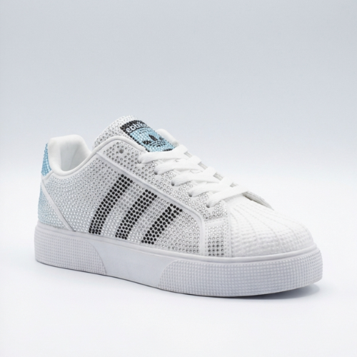  Chaussures de sport à embout rainuré et détails brillants, photographiées en studio sur surface neutre. 