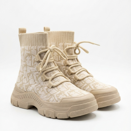 « Deux bottines montantes au design tricoté, placées talon contre talon, photographiées en studio. 