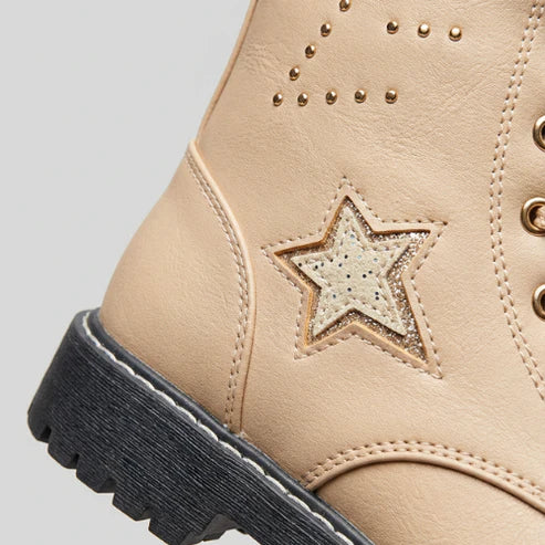 Gros plan sur le détail étoile glitter et les studs dorés d’une botte beige enfant, finition premium.